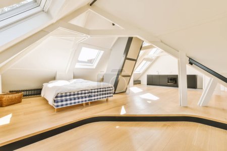 ein Mansardenschlafzimmer mit Holzboden und Oberlichtern über dem Bett, wie auf diesem Foto