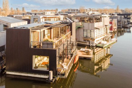 some houses that are floating in the water, and one is on the other side of the houseboats