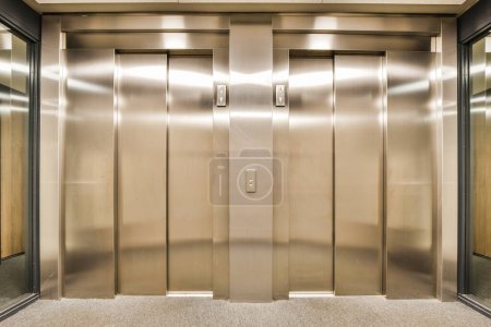 Foto de Dos ascensores en un edificio de oficinas, uno está cerrado y las otras puertas están abiertas con la luz que brilla sobre ellos - Imagen libre de derechos