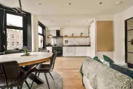 Foto de Una cocina y comedor en un apartamento moderno con paredes blancas, suelos de madera y grandes ventanales con vistas a la calle - Imagen libre de derechos
