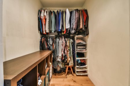 Foto de Un paseo - en el armario con ropa colgando en las paredes y suelos de madera, todo alineado para el almacenamiento - Imagen libre de derechos