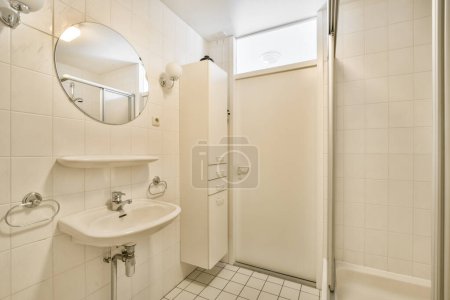 Photo for A bathroom with a sink, mirror and toilet paper dispensed on the wall next to the door - Royalty Free Image