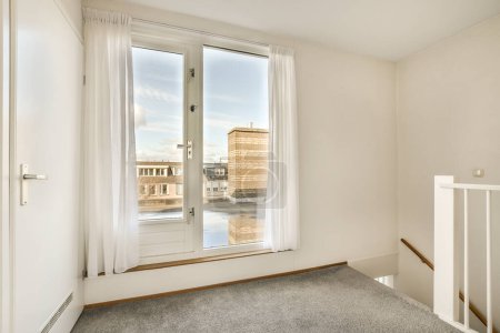 Téléchargez les photos : Une pièce vide avec une fenêtre et des rideaux blancs sur les rebords des fenêtres, donnant sur la rue en contrebas - en image libre de droit