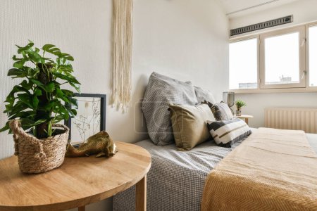 a bedroom with two beds and a plant on the side table in front of the bed that is next to the window