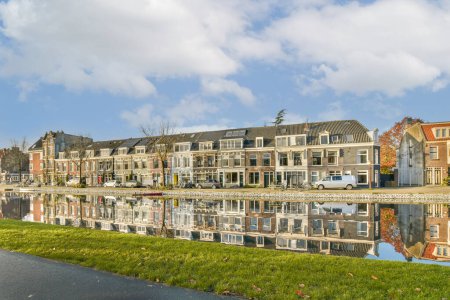 Photo for An urban area with houses on the other side and water reflecting them in the fore - lit watersides - Royalty Free Image