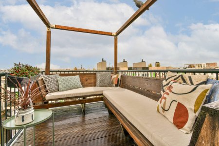 Photo for Amsterdam, Netherlands - 10 April, 2021: an outdoor living area with couches and pillows on the deck overlooking the city skyline in the sky is blue - Royalty Free Image