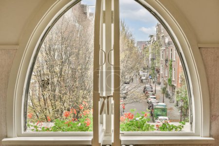 Téléchargez les photos : Amsterdam, Pays-Bas - 10 Avril, 2021 : une vue extérieure depuis une fenêtre avec des fleurs sur les appuis des fenêtres et des arbres dans la zone de premier plan - en image libre de droit