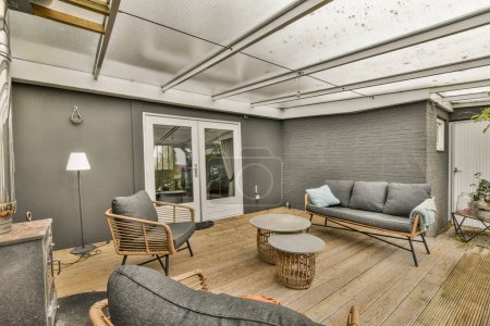 Téléchargez les photos : Un salon avec des canapés, des chaises et une table basse au sol devant une porte coulissante en verre - en image libre de droit