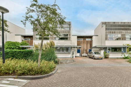 Photo for Amsterdam, Netherlands - 10 April, 2021: an outside area with cars parked in the driveway and trees on either side of the road, surrounded by buildings - Royalty Free Image