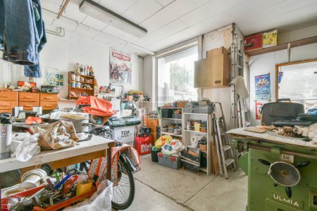 Téléchargez les photos : Un garage désordonné avec beaucoup d'embouteillages sur le sol et des outils dans la zone à utiliser pour le travail - en image libre de droit