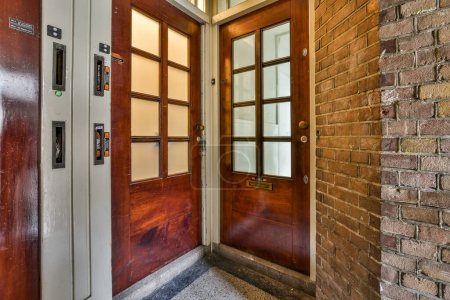 Photo for A brick building with a wooden front door and glass paneled entryway to the left side of the photo - Royalty Free Image