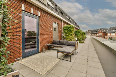 Téléchargez les photos : Amsterdam, Pays-Bas - 10 avril 2021 : un espace extérieur avec des meubles et des plantes sur le côté d'un bâtiment en brique, devant un ciel bleu rempli de nuages blancs - en image libre de droit