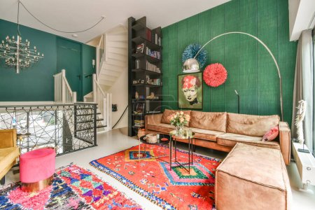 Foto de Una sala de estar con paredes verdes y alfombras de colores en el suelo frente a sofás, mesas de café y sillas - Imagen libre de derechos