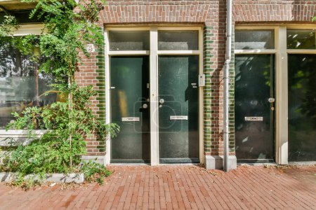 Photo for A brick building with two doors and some plants growing on the side of the building, in front of it - Royalty Free Image