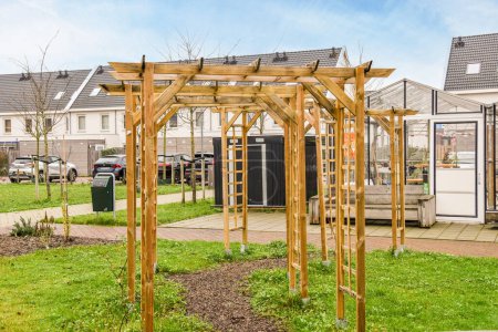 Photo for An outdoor area with a wooden structure in the middle and green grass on the ground next to it, there is a blue sky - Royalty Free Image