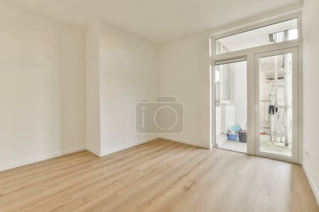 Foto de Una habitación vacía con paredes blancas y suelos de madera en el lado derecho, hay una puerta corredera de vidrio a la izquierda - Imagen libre de derechos