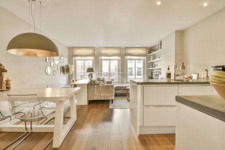 Téléchargez les photos : Une cuisine et salle à manger dans une maison avec planchers de bois, murs blancs, parquet et grandes fenêtres - en image libre de droit