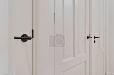 Photo for The inside of a room with white walls and door handles on each side doors are closed to reveal an open doorway - Royalty Free Image