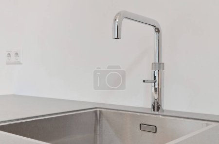 eine Küchenspüle mit dem Wasserhahn auf der linken Seite und einer leeren Wand im Hintergrund