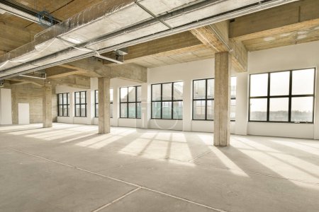 Téléchargez les photos : Un immeuble de bureaux vide avec beaucoup de fenêtres et de lumière venant du soleil qui brille à travers le panorama des fenêtres - en image libre de droit