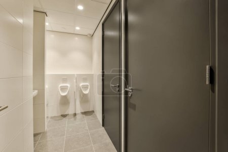 Photo for A bathroom with two urns in the wall and one on the floor next to the url toilet door - Royalty Free Image