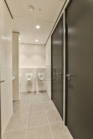 Photo for A bathroom with two toilets in the middle and one on the other side there is an open door that leads to another room - Royalty Free Image