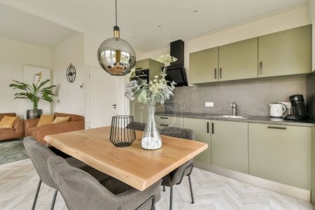 a kitchen and dining area in a modern style home with light green cabinets, white marble flooring and wooden table