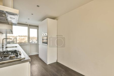 Téléchargez les photos : Une cuisine avec parquet et murs blancs dans un appartement, vue de l'intérieur vers l'extérieur - en image libre de droit