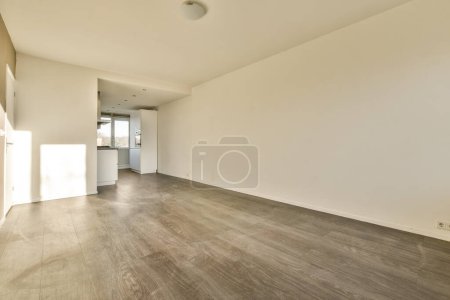 Foto de Una sala de estar vacía con suelos de madera y paredes blancas a cada lado de la habitación, hay luz que viene a través de la ventana - Imagen libre de derechos