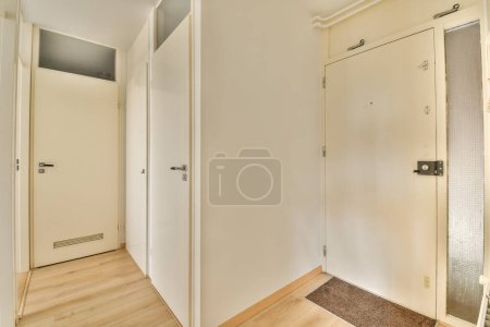 Photo for An empty room with white walls and wood flooring on either side by two doors, one door open to the other - Royalty Free Image