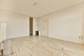 an empty room with white walls and wood flooring on one side, there is a heater in the corner Poster #655183284