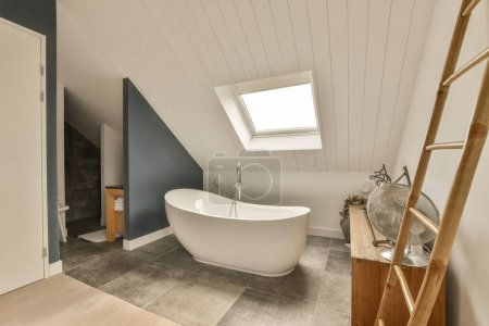 Foto de Un cuarto de baño que está en casa someones, con la claraboya por encima de ella y escaleras de madera que conducen a la bañera - Imagen libre de derechos
