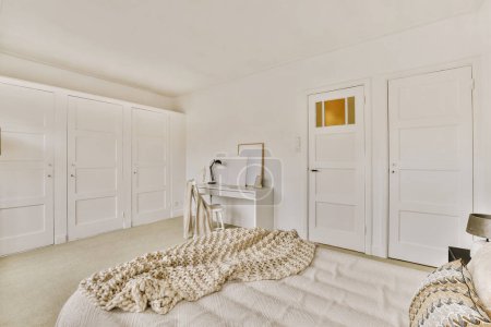 Photo for A bedroom with white closets in the background and a bed that is covered up with a blanket on it - Royalty Free Image