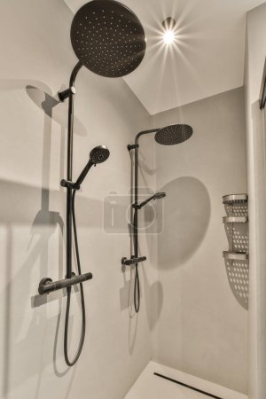 Téléchargez les photos : Une salle de bain moderne avec pomme de douche et douche à main sur le mur en noir et blanc - en image libre de droit