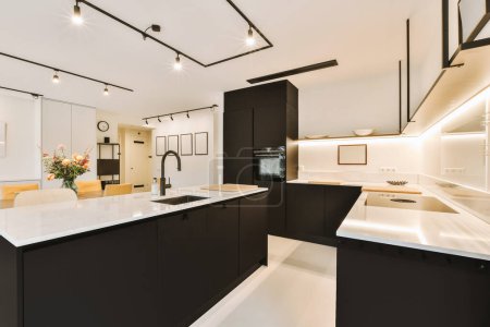 a modern kitchen with black cabinets and white countertops in the center of the image is an open - plan living room