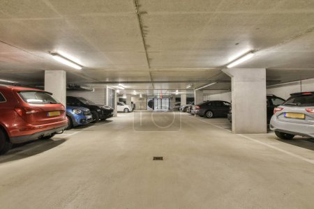 Foto de Un aparcamiento subterráneo con coches estacionados en el espacio entre los otros coches y uno tiene su puerta abierta - Imagen libre de derechos