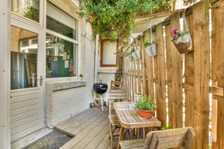 Téléchargez les photos : Un espace extérieur avec des meubles en bois et des plantes sur le côté de la maison qui est utilisé pour les barbecues - en image libre de droit