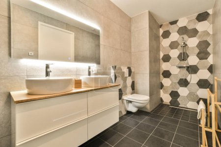 Téléchargez les photos : Une salle de bain avec carrelage hexagonal noir et blanc sur les murs, comptoirs en bois et toilettes dans le coin - en image libre de droit