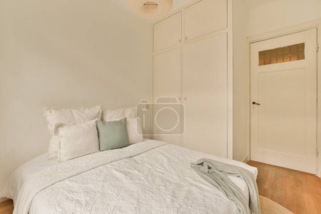 Photo for A bedroom with a bed and closets in the wall behind it is an open door that leads to another room - Royalty Free Image