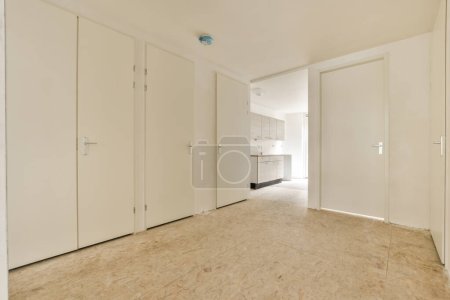 Photo for An empty room with white closets and doors on either side, looking towards the entrance to the living room - Royalty Free Image