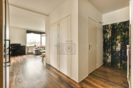 Photo for A living room with wood flooring and white walls, an open door leading to the bedroom is in the background - Royalty Free Image
