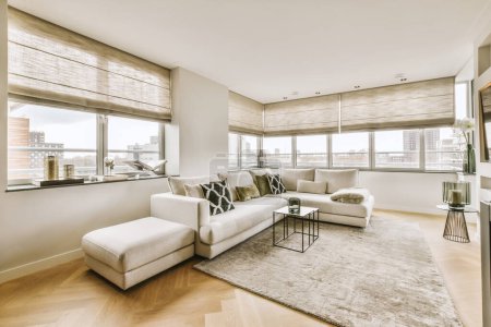 Photo for A living room with hardwood flooring and white couches in front of large windows looking out onto the city - Royalty Free Image