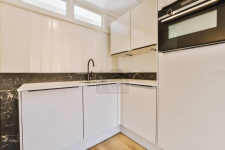 Foto de Una cocina con armarios blancos y encimeras de mármol negro en los mostradores en esta foto se toma desde el interior - Imagen libre de derechos