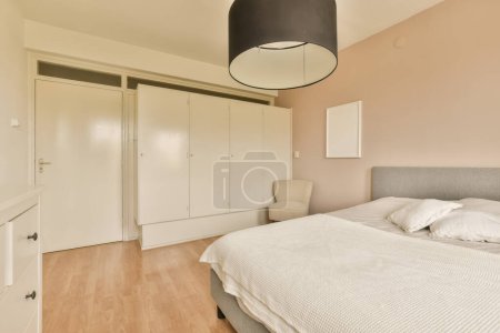 Foto de Un dormitorio con una cama y armarios empotrados en la pared detrás de él es un gran espejo colgando sobre la cama - Imagen libre de derechos