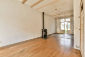 an empty living room with wood flooring and a wood burning stove in the middle part of the room is white walls hoodie #665028042