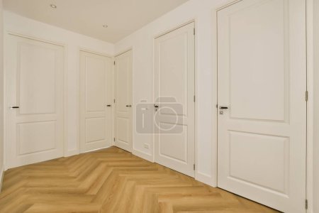 Photo for An empty room with wooden floors and white doors on either side of the room, there is no one door - Royalty Free Image
