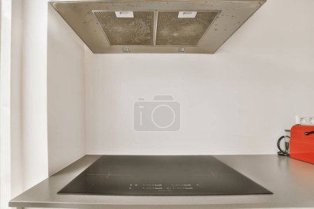 Photo for A stove in the corner of a kitchen with a toaster on its side and an orange kettle sitting next to it - Royalty Free Image