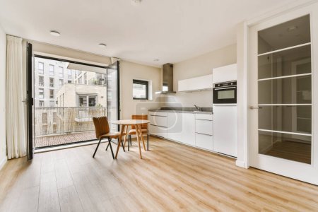eine Küche und ein Essbereich in einer modernen Wohnung mit Glasschiebetüren, die auf den Balkon zu einer Außenterrasse führen