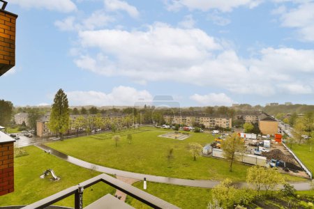 Foto de Una vista desde la parte superior de un edificio con césped verde y edificios en la distancia, en un día soleado - Imagen libre de derechos