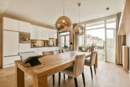 Foto de Una cocina y comedor en una casa moderna con suelos de madera, armarios blancos y una sala de estar abierta - Imagen libre de derechos